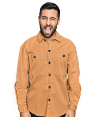 Poster - Young hispanic man wearing casual clothes sticking tongue out happy with funny expression. emotion concept.