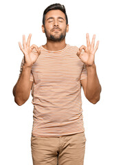 Canvas Print - Handsome hispanic man wearing casual clothes relaxed and smiling with eyes closed doing meditation gesture with fingers. yoga concept.