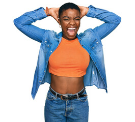 Sticker - Young african american woman wearing casual clothes crazy and scared with hands on head, afraid and surprised of shock with open mouth