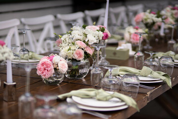 Wall Mural - A large, long, decorated, wooden table and chairs, covered with a white tablecloth with dishes, flowers, candles.