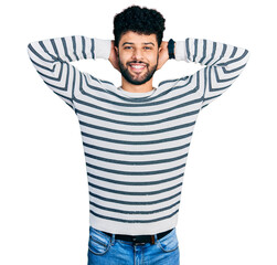 Poster - Young arab man with beard wearing casual striped sweater relaxing and stretching, arms and hands behind head and neck smiling happy