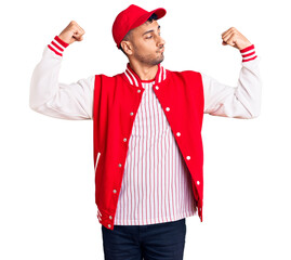 Poster - Young hispanic man wearing baseball uniform showing arms muscles smiling proud. fitness concept.