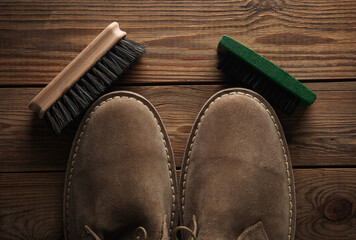 Wall Mural - Suede shoes with brushes on wooden background. Shoe care