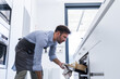 © ADDICTIVE STOCK - Side view of bearded Private chef checking pastry in oven while preparing breakfast in modern kitchen