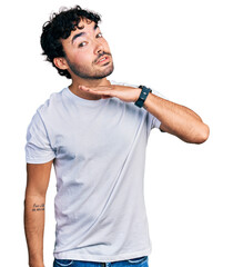 Wall Mural - Hispanic young man with beard wearing casual white t shirt cutting throat with hand as knife, threaten aggression with furious violence