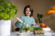 © ADDICTIVE STOCK - Elementary cute girl wearing casuals mixing vegetables with spatula in glass bowl while preparing salad at home