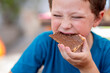 © ADDICTIVE STOCK - Cute hungry boy dressed in casuals with eyes closed eating sweet chocolate spread with bread for breakfast while sitting in restaurant