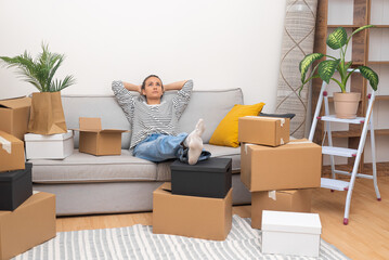 Aufkleber - Woman waits for husband to enjoy new house interior relaxing on comfortable sofa after arranging furniture with sorting out boxes of various decorations for home