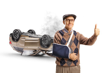 Canvas Print - Elderly man with a broken arm wearing a splint and gesturing thumbs up in front of an accident damaged car