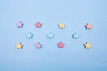 Multicolor wooden stars shapes symbol label form isolated on the bright solid fond plain bright blue background