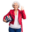 © Krakenimages.com - Senior grey-haired woman holding motorcycle helmet doing ok sign with fingers, smiling friendly gesturing excellent symbol