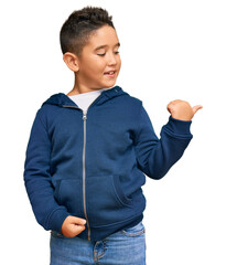 Wall Mural - Little boy hispanic kid wearing casual sporty jacket smiling with happy face looking and pointing to the side with thumb up.