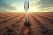 A fork stuck in the middle of a dirt field. Can be used to depict abandonment or a lost object in a desolate location