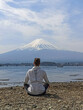 A woman sitting by Kawaguchi Lake with view of Mount Fuji in Japan