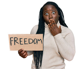 Sticker - Young black woman with braids holding freedom banner covering mouth with hand, shocked and afraid for mistake. surprised expression