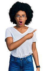 Canvas Print - Young african american woman wearing casual white t shirt surprised pointing with finger to the side, open mouth amazed expression.