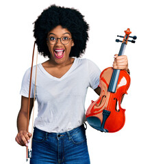 Poster - Young african american woman playing violin celebrating crazy and amazed for success with open eyes screaming excited.