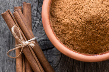 Wall Mural - Cinnamon sticks and cinnamon powder on rustic background, healthy spice, (Cinnamomum)