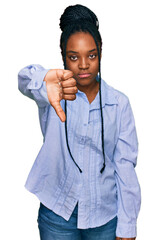 Wall Mural - Young african american woman wearing casual clothes looking unhappy and angry showing rejection and negative with thumbs down gesture. bad expression.