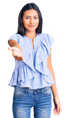 Sticker - Young beautiful latin girl wearing casual clothes smiling cheerful offering palm hand giving assistance and acceptance.