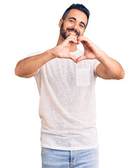 Sticker - Young hispanic man wearing casual clothes smiling in love doing heart symbol shape with hands. romantic concept.