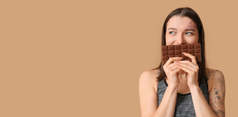 Canvas Print - Sporty young woman holding chocolate bar on beige background with space for text