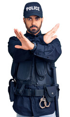 Poster - Young hispanic man wearing police uniform rejection expression crossing arms doing negative sign, angry face