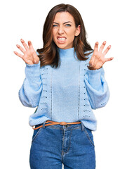 Sticker - Young brunette woman wearing casual winter sweater smiling funny doing claw gesture as cat, aggressive and sexy expression