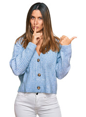 Wall Mural - Young woman wearing casual clothes asking to be quiet with finger on lips pointing with hand to the side. silence and secret concept.