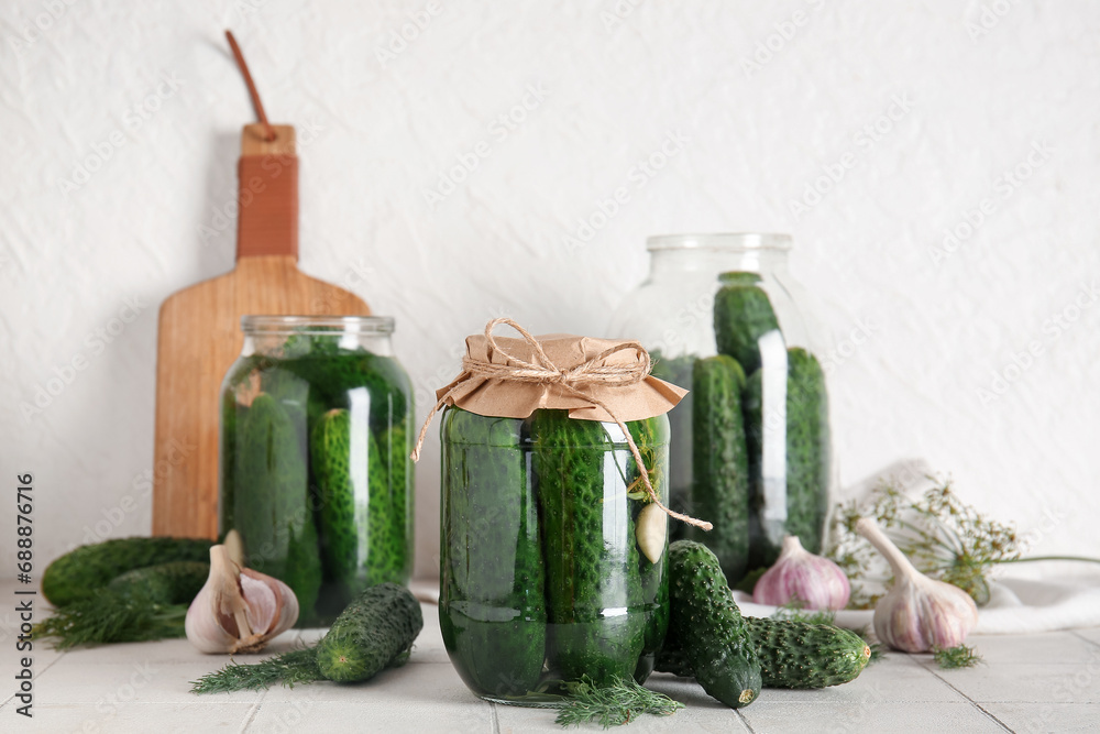 Jars with canned and fresh cucumbers on table