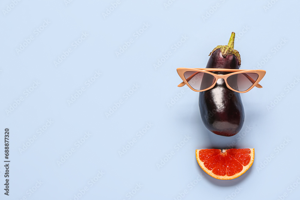 Funny face made of fresh eggplant, grapefruit slice and sunglasses on light background