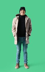 Sticker - Young man in winter clothes on green background