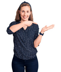 Poster - Young beautiful blonde woman wearing casual shirt amazed and smiling to the camera while presenting with hand and pointing with finger.