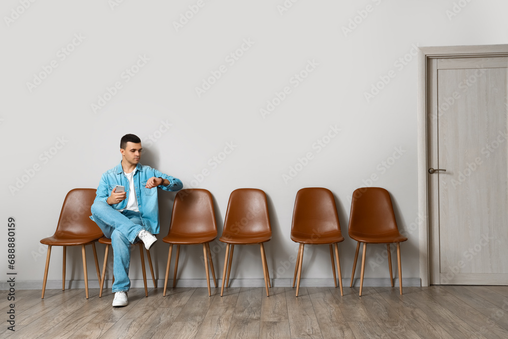 Young man with mobile phone waiting for his turn in room