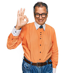 Wall Mural - Middle age indian man wearing casual clothes and glasses smiling positive doing ok sign with hand and fingers. successful expression.