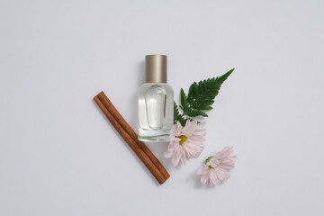 Canvas Print - Mockup scene for advertising perfume product with minimal concept. A glass bottle unbranded decorated with fresh flower, fern leaf and cinnamon stick on white background. Herbal aromatherapy product