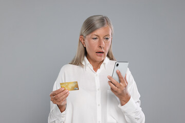 Canvas Print - Worried woman with credit card and smartphone on light grey background. Be careful - fraud