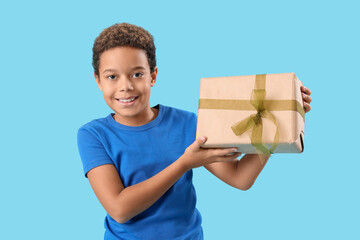 Poster - Little African-American boy with gift box on blue background