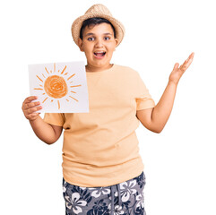 Little boy kid holding sun draw celebrating victory with happy smile and winner expression with raised hands