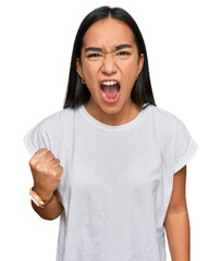 Wall Mural - Young asian woman wearing casual white t shirt angry and mad raising fist frustrated and furious while shouting with anger. rage and aggressive concept.