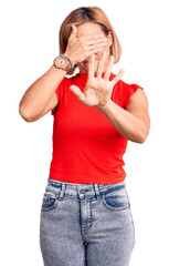 Wall Mural - Young blonde woman wearing casual clothes covering eyes with hands and doing stop gesture with sad and fear expression. embarrassed and negative concept.