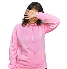 Wall Mural - Young hispanic woman wearing casual sweatshirt covering eyes with arm, looking serious and sad. sightless, hiding and rejection concept
