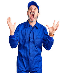 Sticker - Middle age handsome man wearing mechanic uniform crazy and mad shouting and yelling with aggressive expression and arms raised. frustration concept.