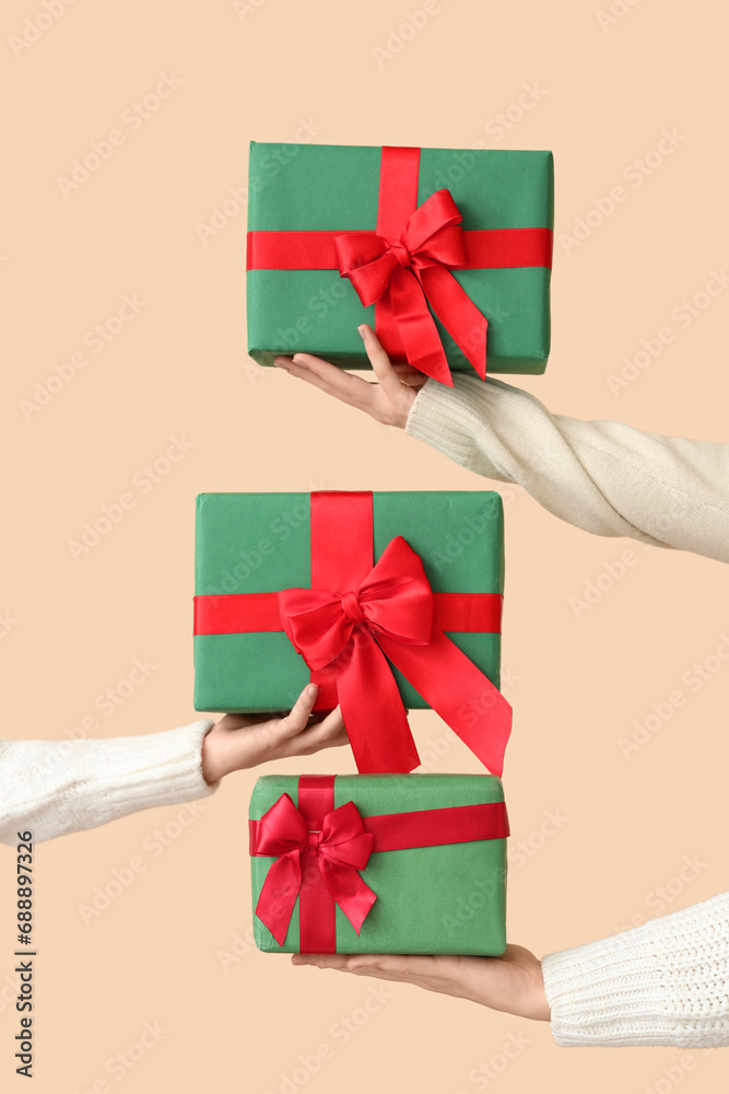 Hands holding Christmas gifts on beige background