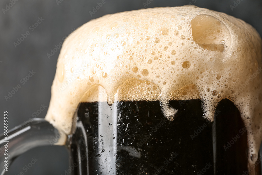 Mug of cold dark beer on black grunge background
