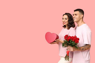 Wall Mural - Loving young couple with gift box and bouquet of beautiful roses on pink background. Celebration of Saint Valentine's Day