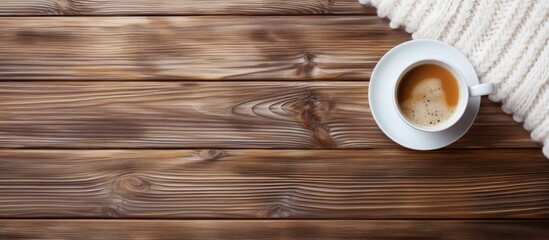 Wall Mural - White knitted sweater and coffee on wooden table, viewed from above.