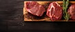 Wooden design board featuring top view of dry aged wagyu rib-eye beef steaks, with copy space