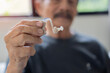 © Kunlathida - Senior man with grey hair holding medical hearing aid smiling happy and positive, doing showing a new one hearing aid.