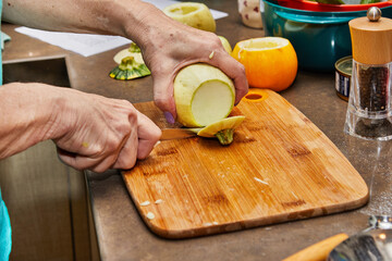 Canvas Print - Chef cuts round zucchini on wooden board in the home kitchen